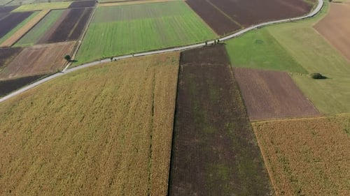 Aerial drone view over country road and agriculture fields after harvest