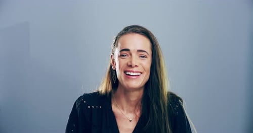 4k video footage of a young woman laughing against a grey studio background