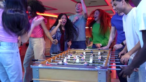 Friends Celebrating Victory Playing Foosball in Bowling Alley