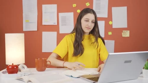 Young Woman Studying and Writing at Desk Indoors