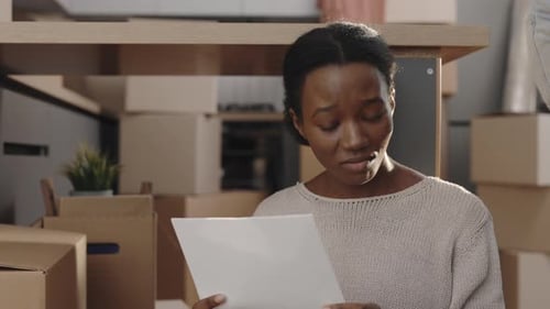 Woman Looks Concerned at Paper During Home Move