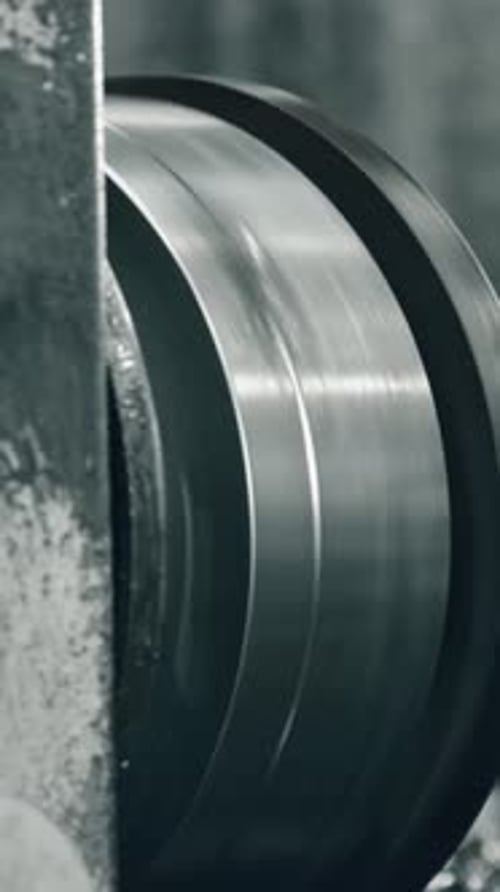 Close-up of metal lathe machine turning cylindrical part in workshop