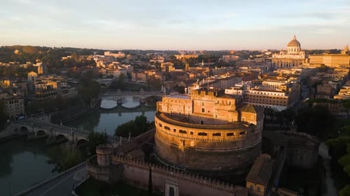 Drone Flies Above Castel Sant'Angelo, River Tiber with St. Peter's Basilica in Background. Sunrise