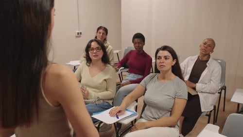 Diverse Group of Female Students Listening to a Teacher During a College Lesson