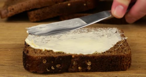 Spreading Butter on Fresh Rye Bread Slice