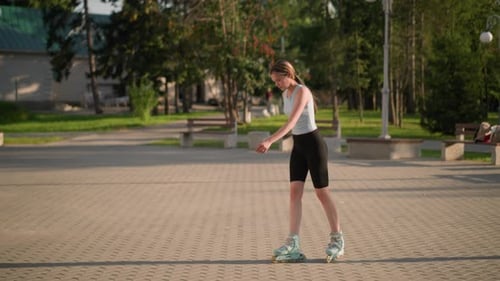 Young Lady Skating Leisurely in Park Surrounded By Greenery and Benches