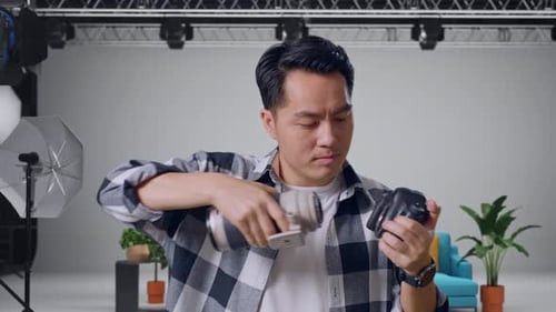 Asian Photographer Changing Lens Of Camera Before Using It Taking Pictures In The Studio
