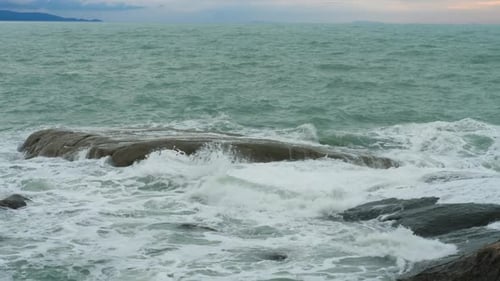Danger Sea Wave Crashing on Rock Coast with Spray and Foam Before Storm