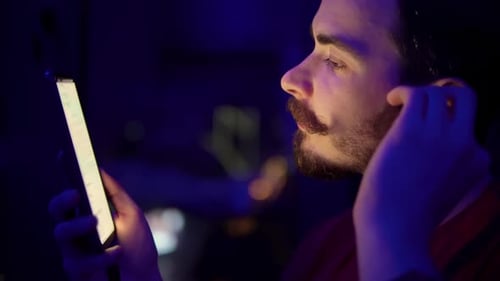 Young Man Using Mobile Phone at Night Indoors