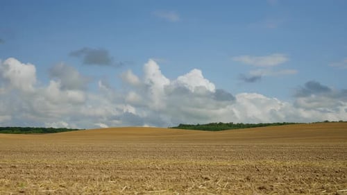 Ploughed Agricultural Field Under Cloudy Sky Brown Soil of a Plowed Field with Remnants of Straw