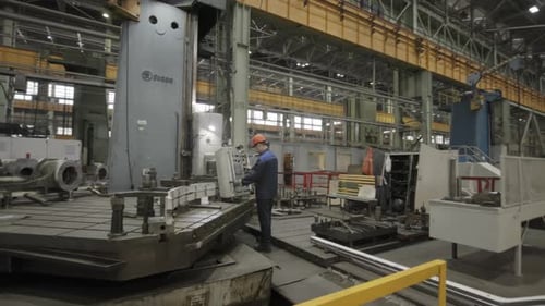 Man Works on Large Industrial Machine in Factory