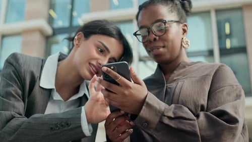 Two Women Looking at Smartphone Outside