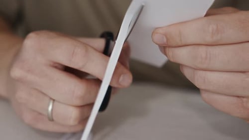 Primer plano de las manos cortando papel blanco con tijeras