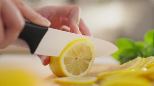 Freshness. A woman with a belly confidently cuts a fresh lemon in a housewife's home kitchen
