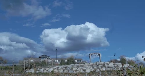 Una bodega se asienta sobre un muro de piedra contra un hermoso cielo azul nublado. La cámara desciende lentamente
por detrás