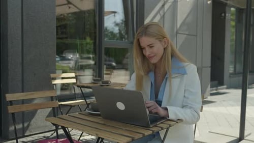 Smiling Businesswoman Waving During Video Call At Outdoor Cafe