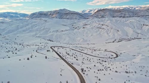 Aerial View of Snow-Covered Mountain Road in Winter Landscape