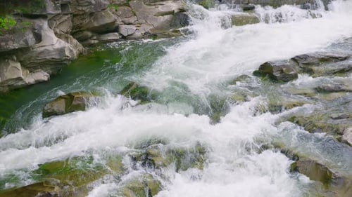 Stormy streams of water and cascades of mountain river waterfalls. Slow motion.