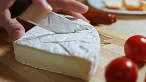 Cutting Brie Soft Cheese on a Wooden Cutting Board Close Up