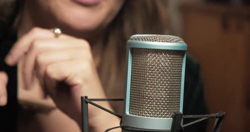 Woman Talking Into Microphone in Recording Studio