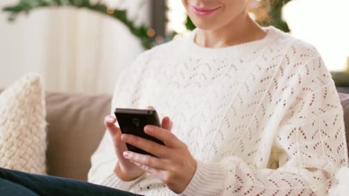 Smiling Woman Relaxing at Home Using Mobile Phone