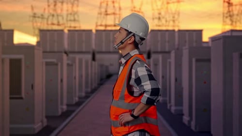 Side View Of Asian Male Engineer Looking Around With Arms Akimbo with High Voltage Power