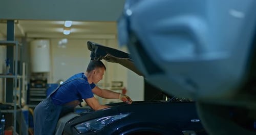Auto Mechanic Repairs a Car at a Service Station
