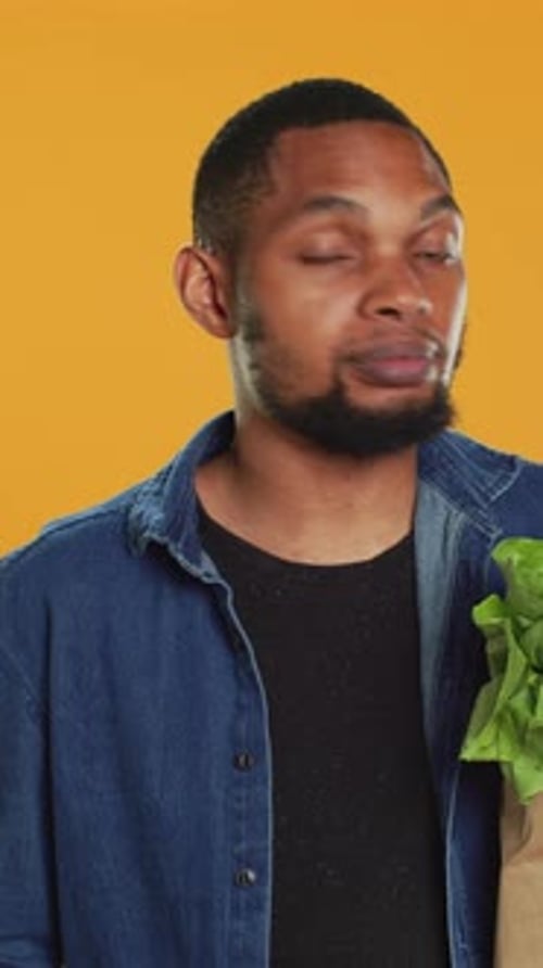 Vídeo vertical: Hombre seguro de sí mismo haciendo malabares con una manzana verde ecológica frente a la cámara