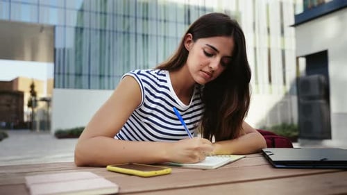 Inspired Hispanic Woman Studying and Writing Notes at the University Student Girl Thinking and