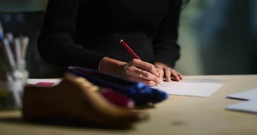 Fashion Designer Sketching Shoe Design at Desk