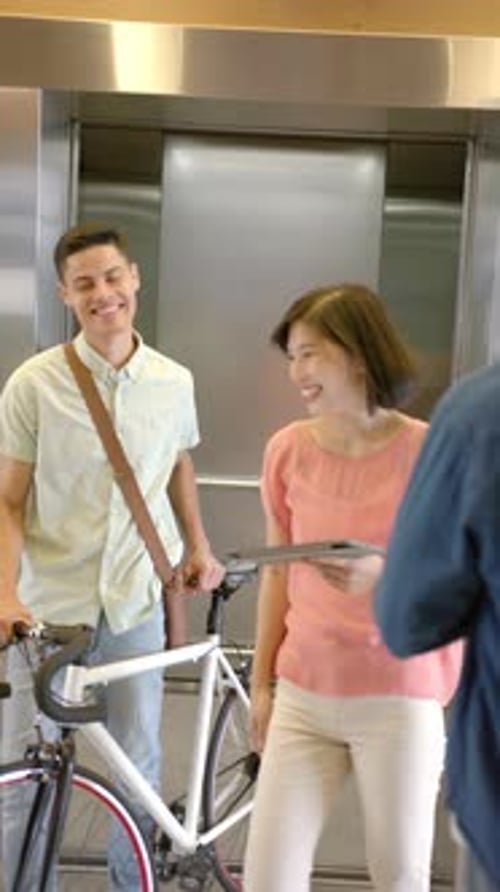 Vertical video: Waiting for elevator, man in denim jacket standing near bicycle in building
