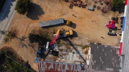 Mobile crane stands waiting to lift steel at a warehouse. Crane operators and mobile cranes