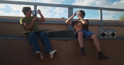 Young friends having fun with vintage film camera at skateboard park during summer time