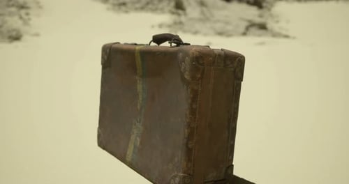 Old Leather Suitcase Resting on Sandy Surface in Deserted Area During Daylight