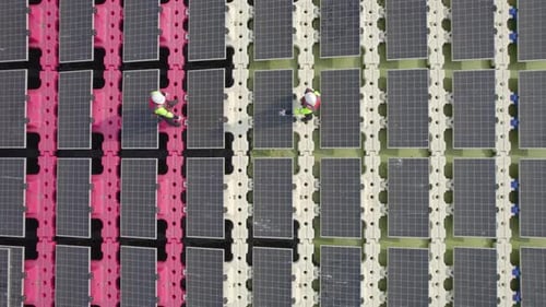 Aerial view of two technician workers stand on walk way of solar cell panel and discuss about work