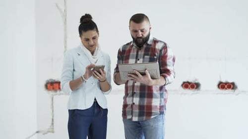 Joven pareja con un teléfono inteligente y una computadora portátil moderna hablando y comprobando un proyecto en