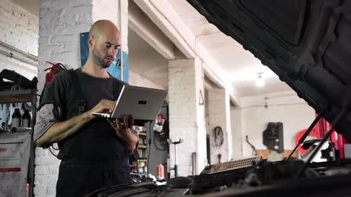 Auto Repairman Diagnoses a Car Using a Computer Car Workshop