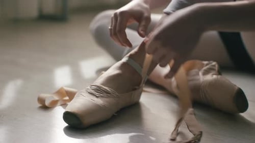 Ballerina Tying Ballet Shoes in the Dance Studio