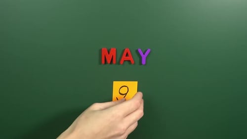 Hand sticking a sticker 9 May calendar day on school board. 9 date of May. Ninth day May. 9Th