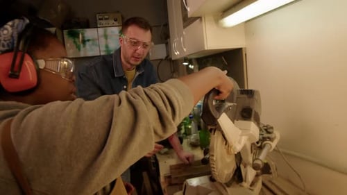 Skilled Carpenter Teaching New Female Workshop Employee to Use Miter Saw