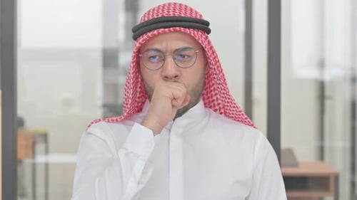 Man in Traditional Dress Coughing Indoors