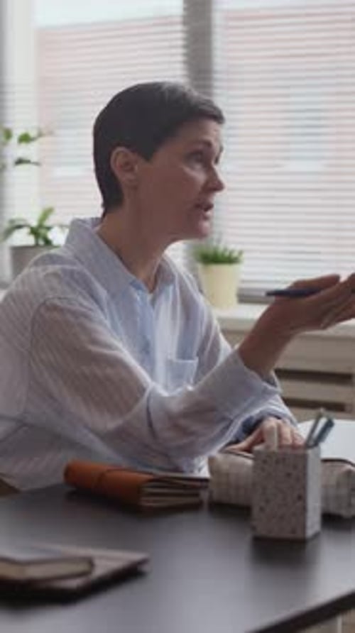 Vertical of Mature Woman Focused on Note Taking during Classroom Lecture