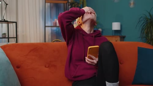 Woman Frowning at Mobile Phone Indoors