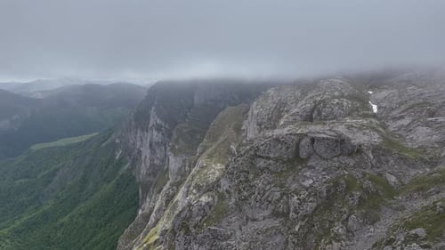 Cliff Picos de Europa Spain high in mountains drone, aerial misty clouds in background