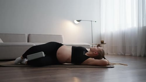 Jeune femme enceinte faisant du yoga et des exercices d'étirement pour soulager les douleurs vertébrales, fitness à domicile
