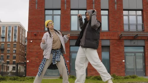 Two Young Adults Dancing in Front of Brick Building