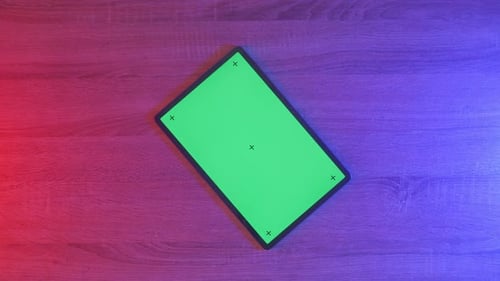 Top down view of a mock up green screen tablet on an neon desk, game concept