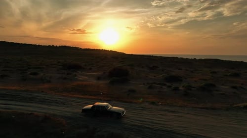 Oldtimer auf unbefestigter Straße bei Sonnenuntergang
