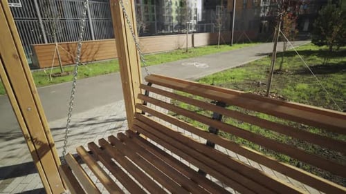 Empty Wooden Bench Swing in Sunny Urban Park