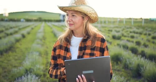 Une
agricultrice agronome marche et tient un ordinateur portable dans ses mains, vérifiant la récolte dans le champ. Moderne